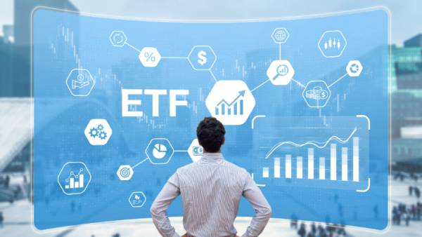 Muž stojí pred obrovským displejom s nápismi ETF, grafmi a symbolmi.