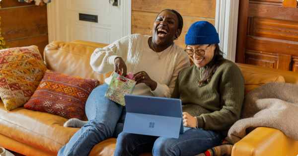 Dos amigos delante de un ordenador en un artículo sobre Invita a un Amigo de XTB